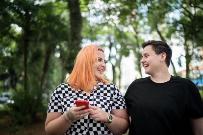 Young couple smiling at each other in the park, one of them has Aries traits such as being adventuro...