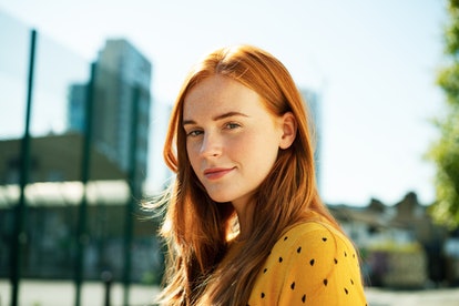 Young Cancer woman looking straight at the camera, wearing a yellow shirt.